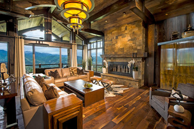 Living room - large rustic open concept dark wood floor and brown floor living room idea in Other with a standard fireplace, a stone fireplace and a concealed tv