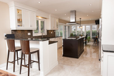 Example of a classic l-shaped ceramic tile eat-in kitchen design in Toronto with a double-bowl sink, recessed-panel cabinets, white cabinets, granite countertops, brown backsplash, ceramic backsplash, stainless steel appliances and an island