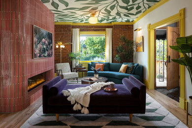 Inspiration for a mid-sized eclectic open concept medium tone wood floor, brown floor, wallpaper ceiling and brick wall living room library remodel in Denver with white walls, a standard fireplace, a tile fireplace and a concealed tv