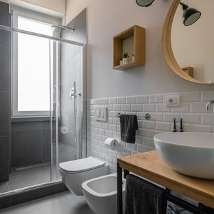 Esempio di una stretta e lunga stanza da bagno con doccia industriale di medie dimensioni con nessun'anta, ante in legno chiaro, doccia alcova, WC a due pezzi, piastrelle bianche, piastrelle in gres porcellanato, pareti grigie, pavimento in gres porcellanato, lavabo a bacinella, top in legno, pavimento grigio, porta doccia scorrevole, un lavabo, mobile bagno freestanding e soffitto ribassato