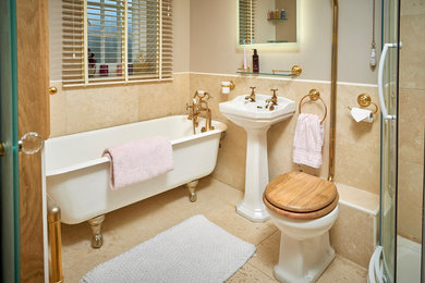 Design ideas for a mid-sized traditional kids bathroom in Buckinghamshire with a claw-foot tub, a corner shower, a two-piece toilet, travertine, beige walls, travertine floors, a pedestal sink and a sliding shower screen.