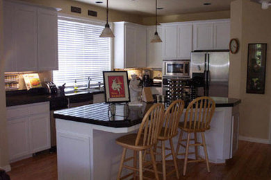 Example of a classic single-wall medium tone wood floor kitchen design in Portland with light wood cabinets, beige backsplash, stainless steel appliances and an island