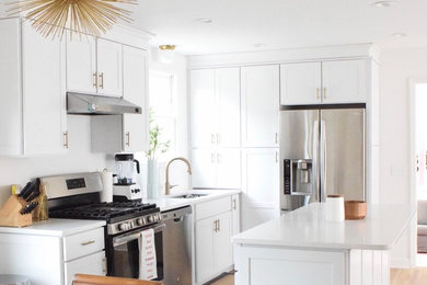 Mid-sized trendy light wood floor and brown floor eat-in kitchen photo in Nashville with white cabinets, marble countertops, white backsplash, subway tile backsplash, stainless steel appliances and an island