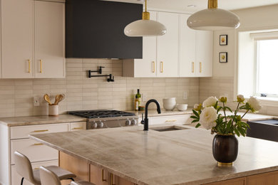 Example of a large danish porcelain tile and beige floor kitchen design in New York with a farmhouse sink, shaker cabinets, white cabinets, quartzite countertops, beige backsplash, subway tile backsplash, paneled appliances and beige countertops