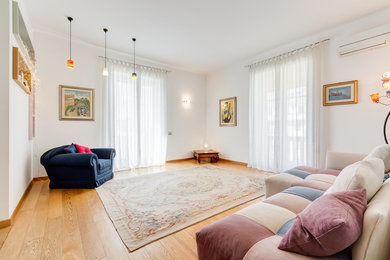 Ispirazione per un ampio soggiorno design aperto con pareti bianche e parquet chiaro