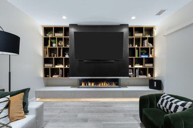Mid-sized trendy open concept laminate floor and gray floor family room photo in Los Angeles with a ribbon fireplace, a stone fireplace and a wall-mounted tv