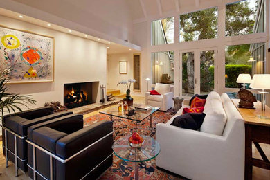 Trendy open concept medium tone wood floor living room photo in Santa Barbara with white walls, a standard fireplace and a plaster fireplace