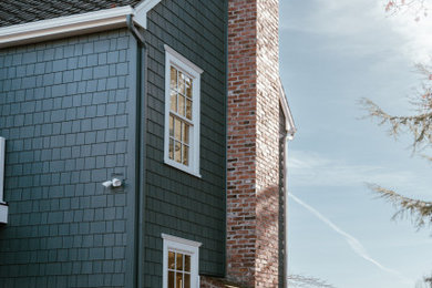 Diseño de fachada de casa azul de estilo americano de dos plantas con revestimiento de aglomerado de cemento, tejado a dos aguas, tejado de teja de madera y teja