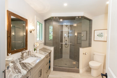 Inspiration for a mid-sized contemporary master gray tile and porcelain tile porcelain tile and beige floor corner shower remodel in Other with recessed-panel cabinets, beige cabinets, a two-piece toilet, beige walls, an undermount sink, granite countertops and a hinged shower door
