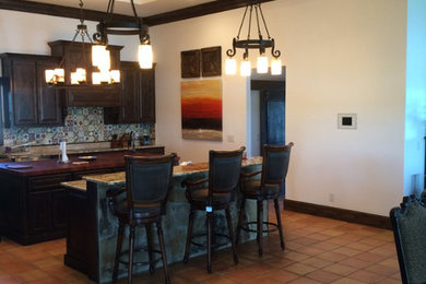 Eat-in kitchen - mid-sized traditional l-shaped terra-cotta tile eat-in kitchen idea in Austin with raised-panel cabinets, dark wood cabinets, limestone countertops, beige backsplash, ceramic backsplash, stainless steel appliances and an island