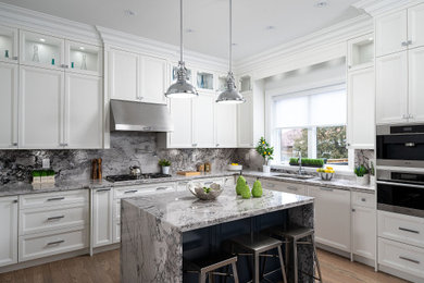 Inspiration for a large modern galley light wood floor and brown floor open concept kitchen remodel in Toronto with a drop-in sink, recessed-panel cabinets, white cabinets, quartz countertops, gray backsplash, quartz backsplash, stainless steel appliances, an island and white countertops