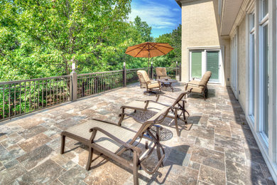 Design ideas for a large traditional backyard patio in Kansas City with natural stone pavers and no cover.