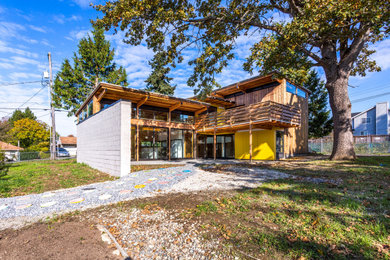 Modelo de fachada de casa amarilla y blanca retro de tamaño medio de dos plantas con tejado de un solo tendido, panel y listón y revestimientos combinados