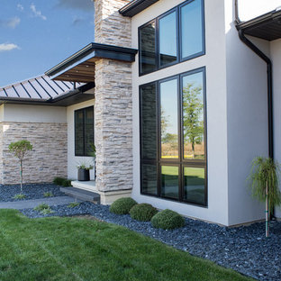 Idéer för mellanstora funkis beige hus, med två våningar, stuckatur, valmat tak och tak i metall