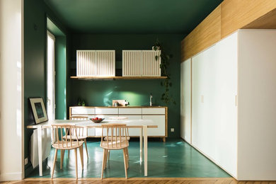 This is an example of a mid-sized contemporary l-shaped open plan kitchen in Paris with a single-bowl sink, white cabinets, wood benchtops, green splashback, panelled appliances and concrete floors.