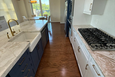 Large transitional l-shaped medium tone wood floor and brown floor eat-in kitchen photo in DC Metro with a farmhouse sink, shaker cabinets, white cabinets, quartz countertops, white backsplash, subway tile backsplash, stainless steel appliances, two islands and beige countertops