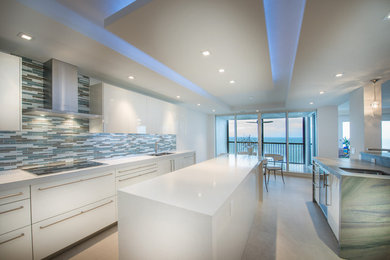 This is an example of a contemporary galley eat-in kitchen in Miami with an undermount sink, flat-panel cabinets, white cabinets, quartz benchtops, multi-coloured splashback and panelled appliances.