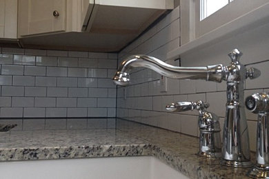 Mid-sized elegant u-shaped eat-in kitchen photo in Cleveland with a farmhouse sink, shaker cabinets, white cabinets, granite countertops, white backsplash, cement tile backsplash, white appliances, no island and gray countertops