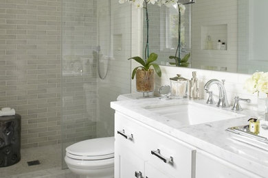Example of a mid-sized transitional 3/4 marble floor and white floor alcove shower design in New York with shaker cabinets, white cabinets, a two-piece toilet, white walls, an undermount sink, marble countertops, a hinged shower door and white countertops