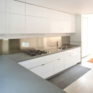 Cette photo montre une arrière-cuisine tendance en L de taille moyenne avec un évier encastré, un placard à porte plane, des portes de placard blanches, un plan de travail en quartz, une crédence métallisée, une crédence en dalle métallique, un électroménager en acier inoxydable, un sol en bois clair et une péninsule.