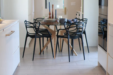 Kitchen - mid-sized modern galley porcelain tile and gray floor kitchen idea in Los Angeles with a single-bowl sink, flat-panel cabinets, white cabinets, white backsplash, stainless steel appliances, no island and white countertops