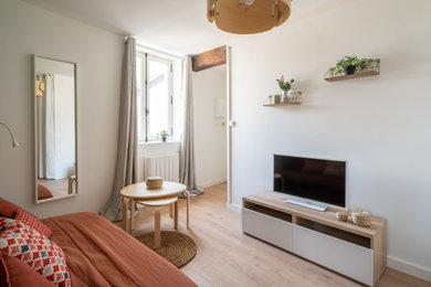 Modelo de salón abierto y blanco contemporáneo pequeño sin chimenea con paredes beige, suelo de madera clara, televisor independiente, suelo beige y cortinas