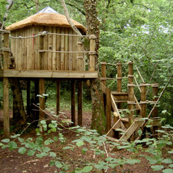 Thatched treehouse hidden in the woods with cornered staircase heading up into t - Garden Playhouses