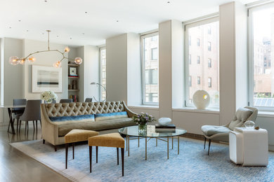 Transitional open concept living room in New York with white walls, light hardwood floors and beige floor.