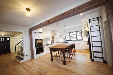 Kitchen - large transitional u-shaped medium tone wood floor kitchen idea in Other with a farmhouse sink, shaker cabinets, white cabinets, solid surface countertops, white backsplash, subway tile backsplash, stainless steel appliances and an island