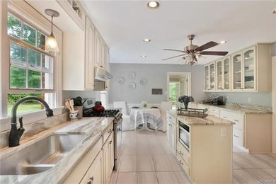 Enclosed kitchen - mid-sized traditional u-shaped porcelain tile and beige floor enclosed kitchen idea in Richmond with a double-bowl sink, shaker cabinets, white cabinets, marble countertops, window backsplash, stainless steel appliances and an island