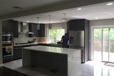 Photo of a medium sized contemporary u-shaped kitchen/diner in Other with a single-bowl sink, flat-panel cabinets, black cabinets, composite countertops, white splashback, stone slab splashback, stainless steel appliances, laminate floors and an island.