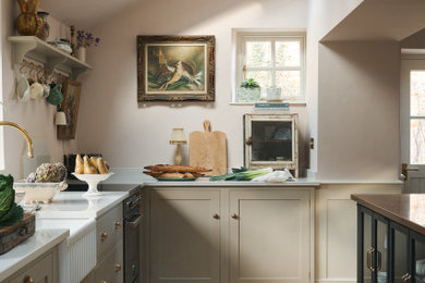 Design ideas for a classic l-shaped kitchen in Other with a belfast sink, shaker cabinets, beige cabinets, stainless steel appliances, medium hardwood flooring, an island, brown floors, white worktops and a vaulted ceiling.