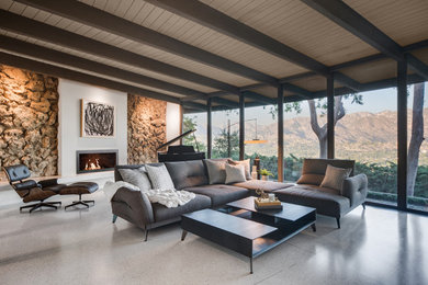 This is an example of a midcentury open concept living room in Los Angeles with a ribbon fireplace, a plaster fireplace surround and white floor.