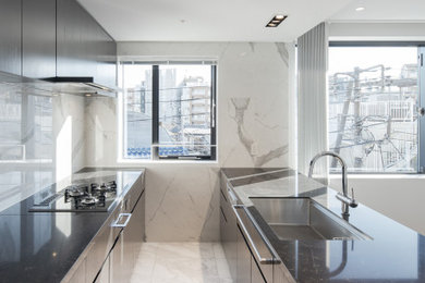 This is an example of a large contemporary single-wall open plan kitchen in Tokyo with an undermount sink, beaded inset cabinets, grey cabinets, quartz benchtops, white splashback, ceramic splashback, black appliances, marble floors, with island, white floor and grey benchtop.