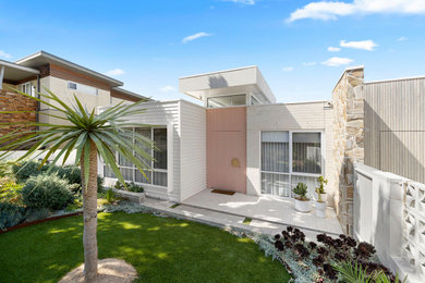 Inspiration for a mid-sized midcentury front yard full sun xeriscape in Melbourne with a retaining wall and natural stone pavers.