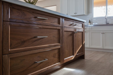 Inspiration for a large transitional u-shaped light wood floor eat-in kitchen remodel in San Luis Obispo with an undermount sink, shaker cabinets, white cabinets, quartz countertops, white backsplash, porcelain backsplash, stainless steel appliances, an island and brown countertops