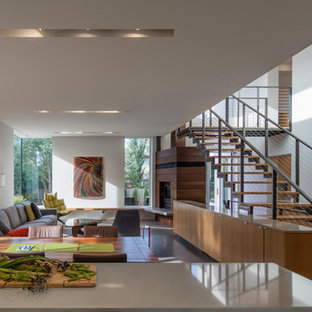 Modern open plan dining in Edmonton with white walls, concrete floors, a corner fireplace, a wood fireplace surround and grey floor.