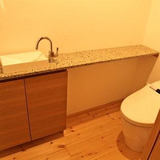 Foto di un bagno di servizio minimalista con ante a filo, ante beige, WC monopezzo, pareti bianche, parquet chiaro, lavabo da incasso, top in zinco e pavimento beige