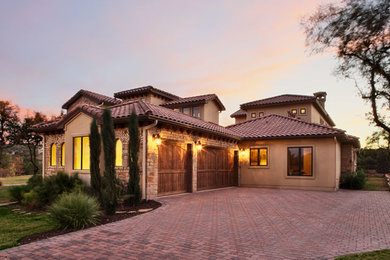 Mid-sized mediterranean beige two-story stucco house exterior idea in Austin with a tile roof