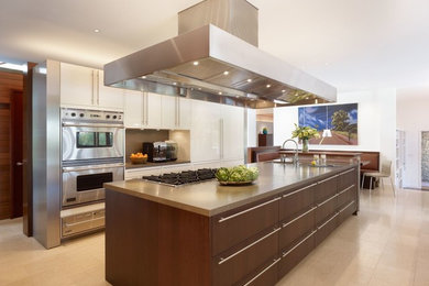 Mid-sized trendy single-wall travertine floor eat-in kitchen photo in Miami with a double-bowl sink, beaded inset cabinets, white cabinets, terrazzo countertops, brown backsplash, stainless steel appliances and an island