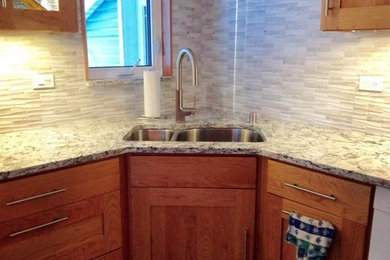 Example of a mid-sized transitional u-shaped medium tone wood floor enclosed kitchen design in Other with an undermount sink, shaker cabinets, dark wood cabinets, granite countertops, gray backsplash, stone tile backsplash, white appliances and no island