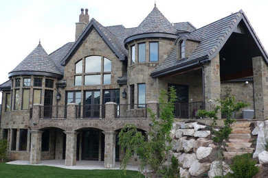 Example of a huge three-story stone exterior home design in Salt Lake City with a clipped gable roof