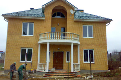 Стильный дизайн: двухэтажный, кирпичный, желтый дом среднего размера в классическом стиле с вальмовой крышей - последний тренд