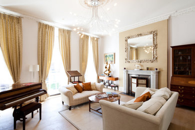 Traditional enclosed living room in London with white walls, light hardwood floors, a standard fireplace and beige floor.