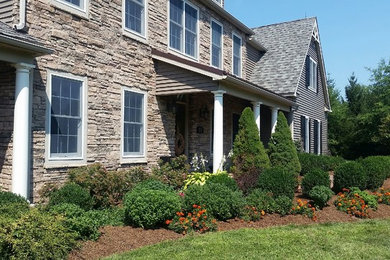 This is an example of a mid-sized farmhouse full sun backyard mulch landscaping in New York.