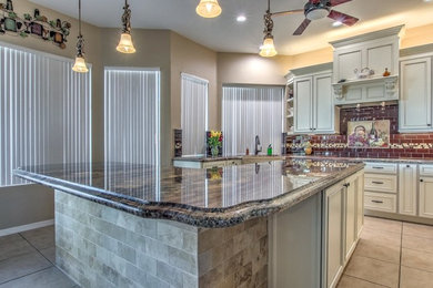 Mid-sized contemporary eat-in kitchen in Phoenix with a farmhouse sink, beaded inset cabinets, white cabinets, granite benchtops, red splashback, subway tile splashback, stainless steel appliances, ceramic floors, with island, beige floor and multi-coloured benchtop.
