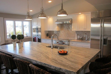 Large beach style galley porcelain tile and brown floor eat-in kitchen photo in New York with a drop-in sink, shaker cabinets, white cabinets, quartzite countertops, beige backsplash, subway tile backsplash, stainless steel appliances and an island