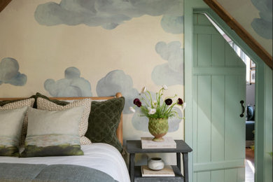 Foto de habitación de invitados de tamaño medio con paredes beige, suelo de madera pintada, todas las chimeneas, marco de chimenea de piedra, suelo verde, vigas vistas y papel pintado