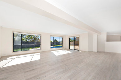 Photo of a large contemporary open concept family room in Canberra - Queanbeyan with a game room, white walls, laminate floors, no fireplace, a freestanding tv and grey floor.