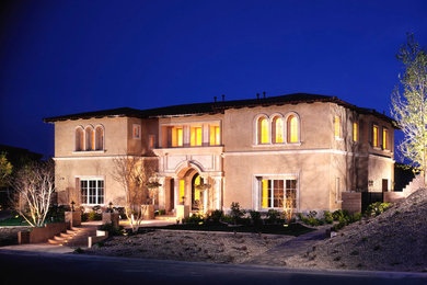 This is an example of a large mediterranean two-storey stucco beige house exterior in Orange County with a gable roof and a tile roof.